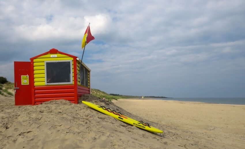 red and blue wooden shed on beach shore during daytime
