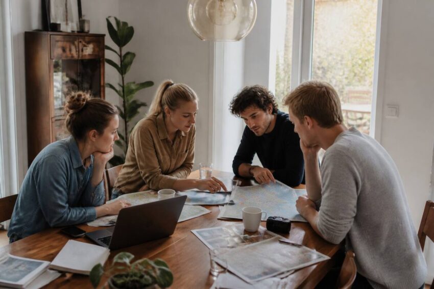 Een reisnotitie-checklist op tafel met laptop en landkaart voor het vergelijken van vakanties